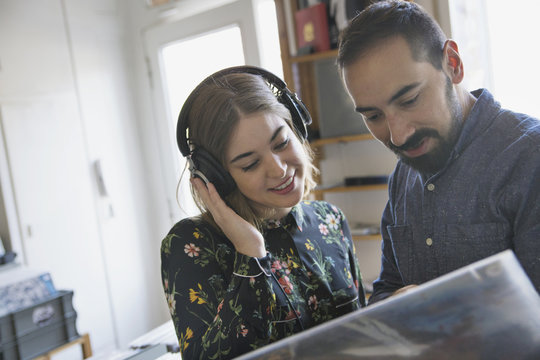 Young couple listening to music with headphones in store for buying records