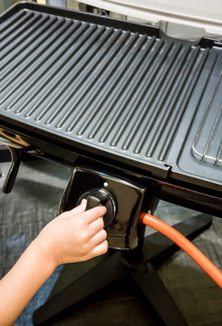 Kid hand adjusting electric pan knob