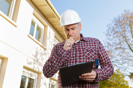 builder in hardhat with clipboard and pencil outdoors