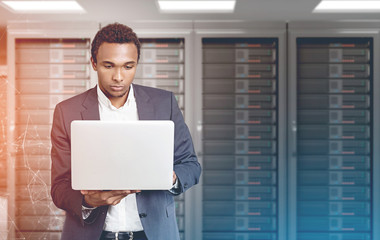 African American man with laptop in a server room