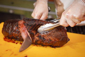 A large roast beef cook cuts into pieces