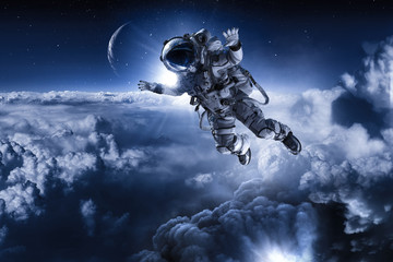 Fototapeta na wymiar Astronaut floating above clouds