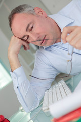 tired businessman with eyeglasses in office