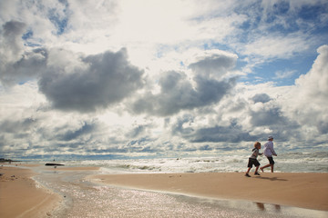 Children running on the beach on a cloudy windy day