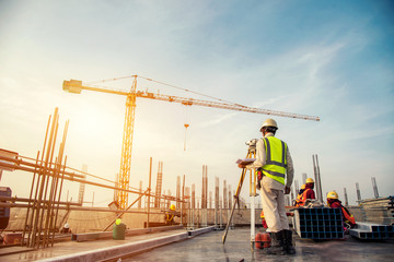 Surveyor builder Engineer with theodolite transit equipment at construction site outdoors during surveying work - obrazy, fototapety, plakaty