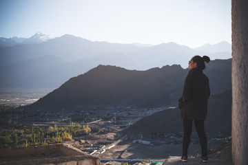 Fototapeta na wymiar Portrait image of a beautiful Asian woman standing on the top of view point with Leh city background