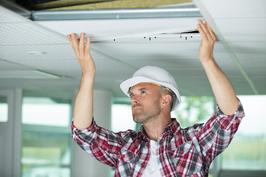 man installing suspended ceiling in house