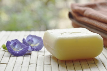 soap and towel with blue pea violet flower on bamboo mat