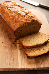 
Freshly baked pumpkin bread loaf on cutting board with knife on dark wood background vertical shot
