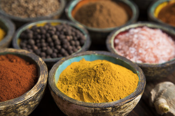 Various colorful spices on a wooden table in bowls