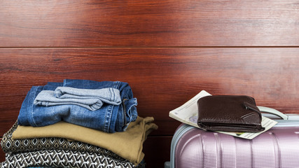 Women's things lie at the closet with things with suitcase and men's wallet the concept of preparing for a trip