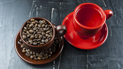 Cup with coffee beans with a red  cup on a dark background