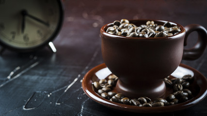 Cup of coffee beans with alarm clock