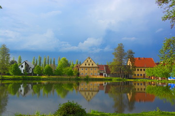 Fototapeta premium Reflection of houses on the water surface in the town of Ustek. Blue sky with clouds. Czech landscape.