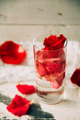 glass delicious refreshing drink of rose petal flower on blue wooden background, infusioned water
