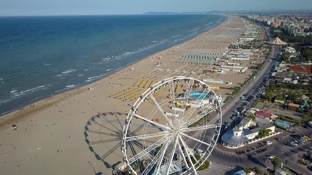 The turing ferries wheel on the side of the coastal beach of Rimini and the hundreds of chairs and umbrellas for the beach goers