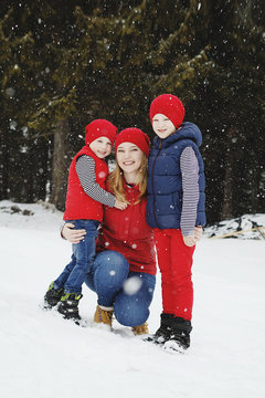 Mother and her two sons having fun in winter in snow forest