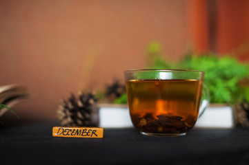Autumn photography with books, a cup of tea, cones, branches of a Christmas tree. On a black wooden background lie books and a cup of tea. A card with a place for your text.