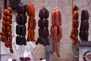 Variety of dried meat sausages hanging in a market shop
