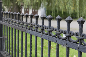 Decorative forgive on metal vintage fence with spikes. Wrought iron protective barrier.