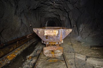 Underground abandoned ore mine shaft tunnel gallery with ore cart