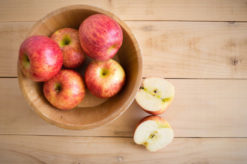 Red apples in a wooden bowl on a wooden background