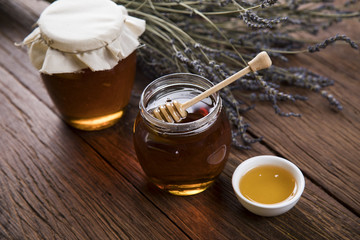 Honey and wooden stick are on a table