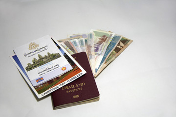 The concept of travel in Cambodia. The pile of document, Arrival and Cambodia departure card on the postcard on the Thai passport on the Cambodian banknotes with white background.