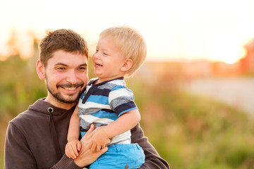 Naklejka na ściany i meble Father and son outdoor portrait in sunset sunlight