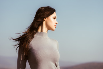 Girl or woman with long brunette hair in grey sweater
