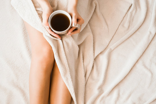 Young woman drinking and enjoying morning coffee in the bed. Wake up concept. Peaceful atmosphere.
