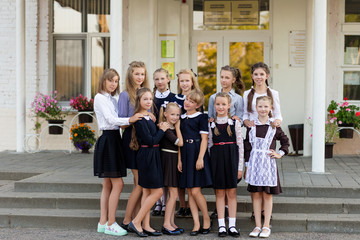 A group of schoolgirls in school uniform faces the school