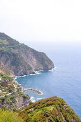 Fototapeta na wymiar View from mountains to blue sea. Water smashing rocks. Riomaggiore, Italy