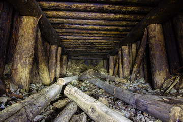 Abandoned old chromite mine shaft tunnel with wooden timbering