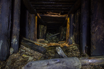 Abandoned old chromite mine shaft tunnel with wooden timbering