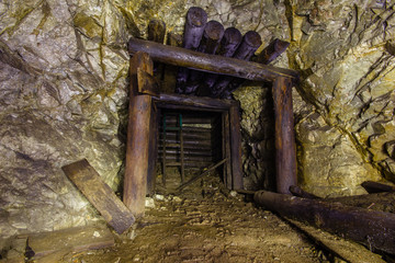 Underground abandoned old mine shaft iron copper gold ore tunnel gallery with wooden stands timbering