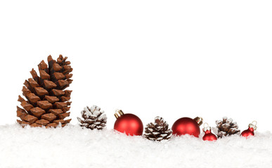 Tannenzapfen und rote Weihnachtskugeln auf Schnee