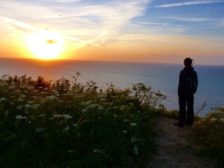 Woman watch sunset on cliff at sea in Normandy France