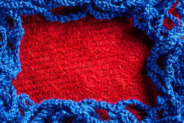 Blue knitted thread on a red fabric background and space for text