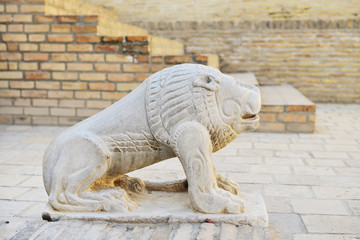 Ancient stone lion sculpture against brick wall, Bukhara, Uzbekistan