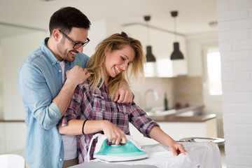 Young couple at home doing hosehold chores and ironing