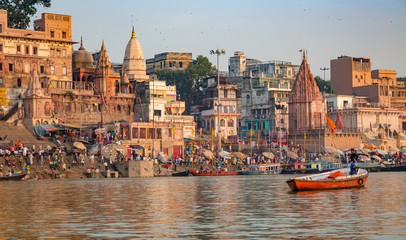 Ancient Varanasi city with old architectural buildings and temples along the Ganges river ghat as viewed from a boat.