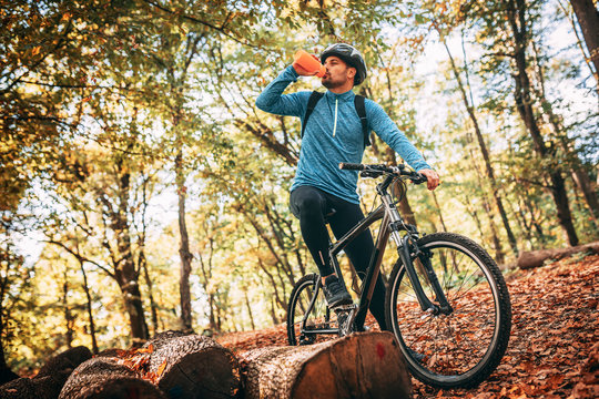 Young Handsome Man Biking Through Forest