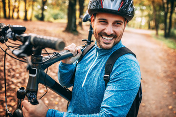 Young man is cycling through forest