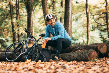 Young handsome man cycling through forest