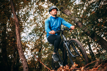 Young man biking through forest