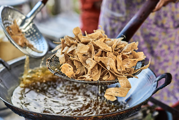 Cooking deep fried chips in boil yellow oil in big metal pan. Traditional asian street food from Langkawi island in Malaysia.