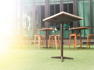 Fototapeta na wymiar Blurred wood table and chair table on artificial green grass background