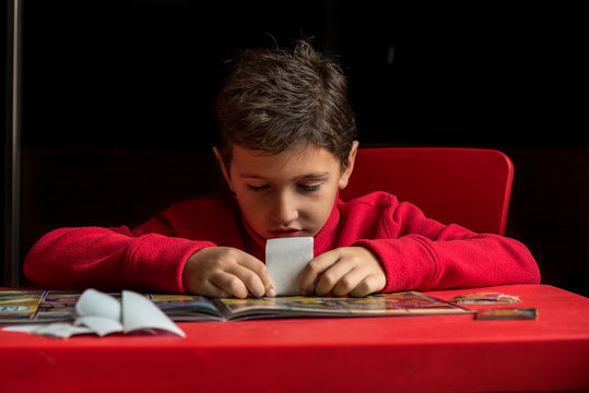 Boy sticking stickers in album on the table
