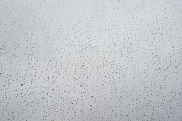raindrops on window glass with cloudy sky as background